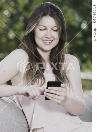 Female is sitting and chatting in phone on the bench Female is sitting and chatting in phone on the bench 34744218
