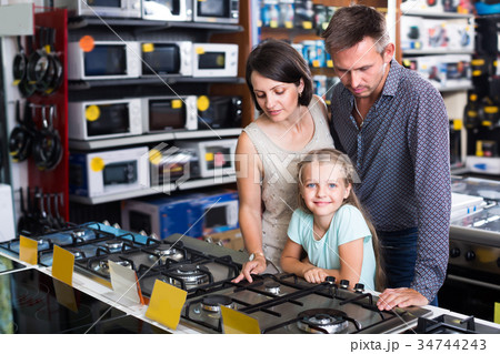 Adult family of three choosing new cooking plate Adult family of three choosing new cooking plate 34744243