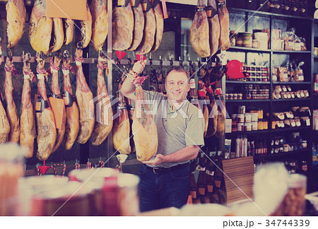 Customer holding jamon leg in local delicatessen shop Customer holding jamon leg in local delicatessen shop 34744339