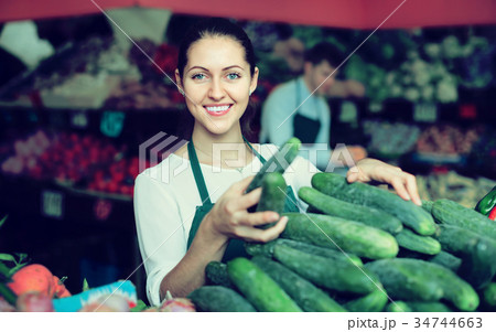 Stuff in apron selling green cucumber at marketplace Stuff in apron selling green cucumber at marketplace 34744663