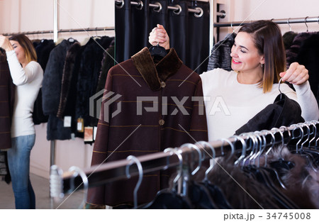 Adult girl deciding on warm brown coat Adult girl deciding on warm brown coat 34745008