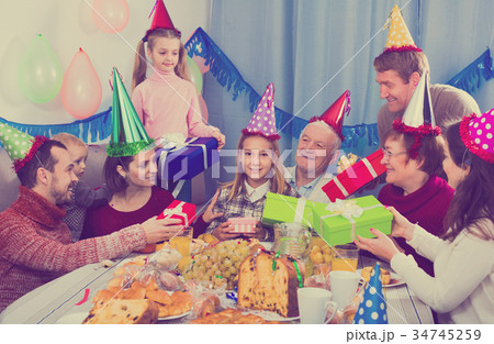Large family presenting gifts to girl during birthday party 34745259