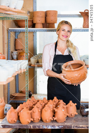Portrait of glad woman pottery worker with ceramic crockery Portrait of glad woman pottery worker with ceramic crockery 34745505