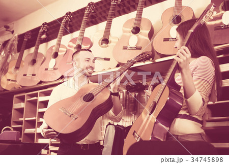 Young couple choosing acoustic guitar in shop 34745898