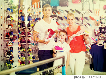 Couple with boy choosing shoes in sport shop Couple with boy choosing shoes in sport shop 34746012