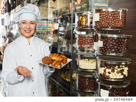 Elderly smiling seller with dark and white chocolates 34746484