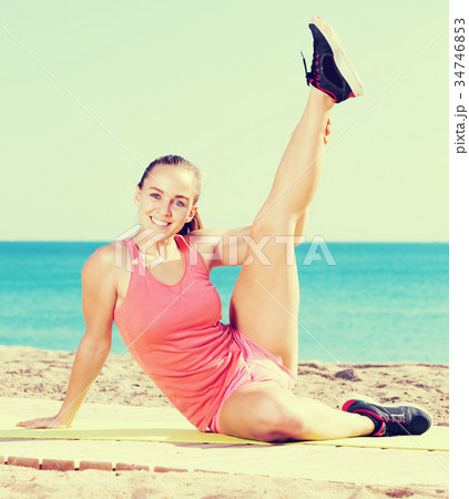 Young sportwoman training gymnastics at sea beach Young sportwoman training gymnastics at sea beach 34746853