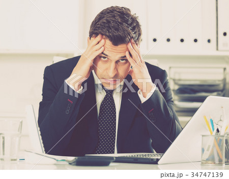 Frustrated businessman at office desk Frustrated businessman at office desk 34747139