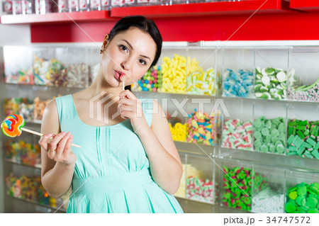 Smiling girl sucking lollypop in store Smiling girl sucking lollypop in store 34747572