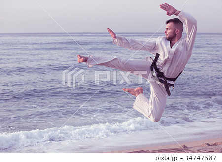 Cheerful man practising karate kata poses 34747587
