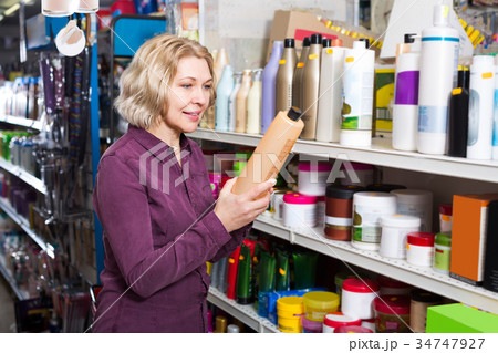 Mature woman selecting shampoo in store. 34747927