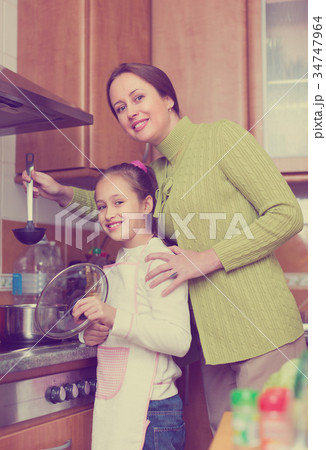 Mother with daughter cooking at kitchen Mother with daughter cooking at kitchen 34747964