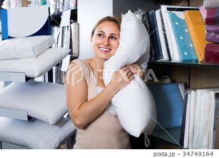portrait of female customer choosing pillow in bedding section in shop 34749164