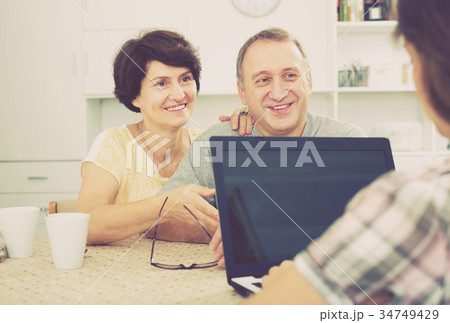 Couple listening to woman with laptop Couple listening to woman with laptop 34749429