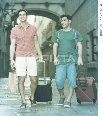 Two men friends walking together with baggage Two men friends walking together with baggage 34749718