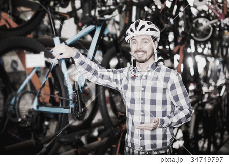 Man in helmet chooses convenient bike Man in helmet chooses convenient bike 34749797