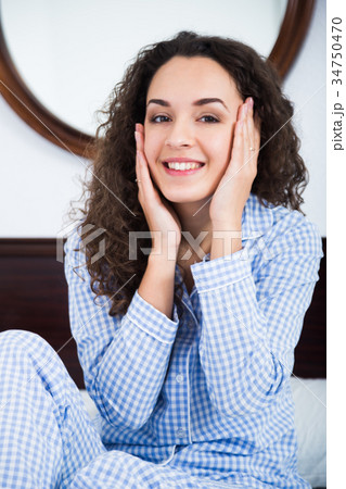 Girl sitting in bed and massaging face Girl sitting in bed and massaging face 34750470