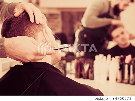 Adult man hairdresser making haircut to client Adult man hairdresser making haircut to client 34750572