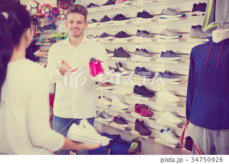 Male seller demonstrating sneakers to female 34750926