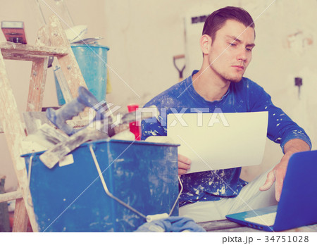 Male contractor working with papers and laptop Male contractor working with papers and laptop 34751028
