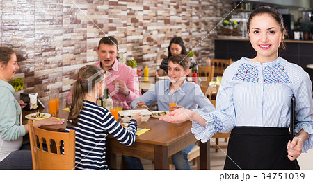 Professional waitress holding tray with dishes meeting visitors Professional waitress holding tray with dishes meeting visitors 34751039