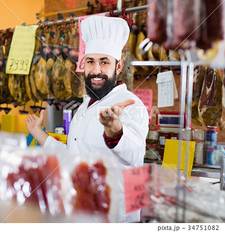Man seller showing sorts of meat in butcher’s shop Man seller showing sorts of meat in butcher’s shop 34751082