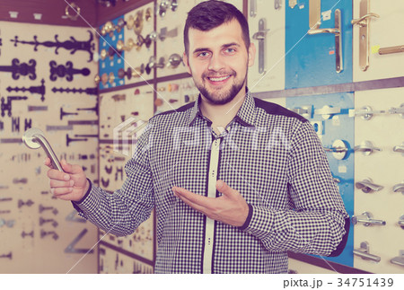 positive male customer examining various door handles in store 34751439