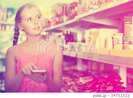 Portrait of blonde girl teenager touch phone screen in the supermarket 34751522