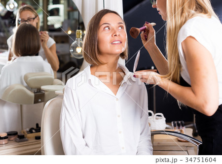 female makeup artist applying cosmetics for woman 34751604