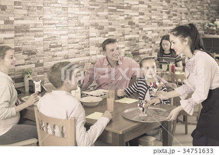 attentive brunette waitress serving family in family cafe 34751633