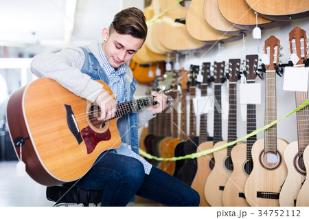 Young boy is choosing quality acoustic guitar Young boy is choosing quality acoustic guitar 34752112