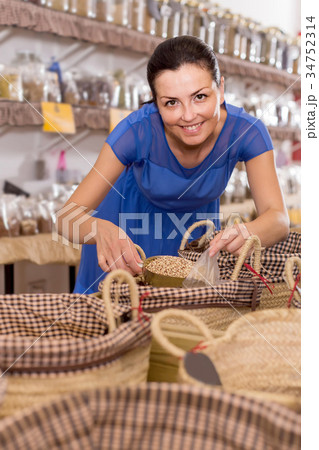 woman taking dried beans with shovel from backet in organic shop 34752314