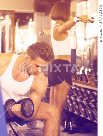 well trained man training hands using heavy weight dumbbells in gym indoors well trained man training hands using heavy weight dumbbells in gym indoors 34752355