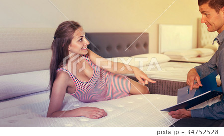 Woman selecting new mattress and store seller 34752528