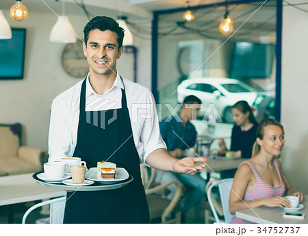 Waiter holding served tray meeting visitors at pastry bar Waiter holding served tray meeting visitors at pastry bar 34752737