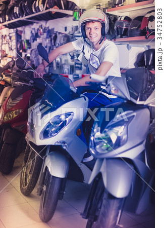 Portrait of glad male in helmet on motorbike in the store 34752803