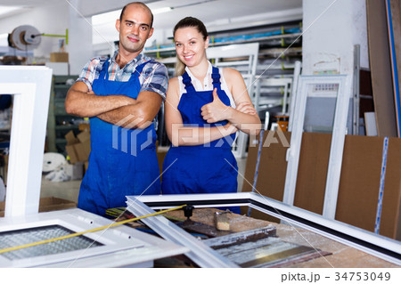Man and woman in blue overalls standing with hands crossed at workplace 34753049