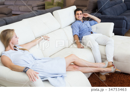 Positive couple choosing new sofa and sitting 34753463