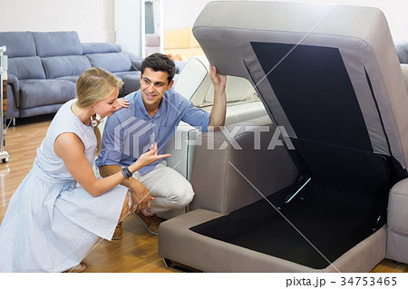 Happy couple are choosing new sofa with a rising bottom in store Happy couple are choosing new sofa with a rising bottom in store 34753465