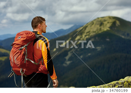 Guy with a travel backpack on the top of a boulder Guy with a travel backpack on the top of a boulder 34760199