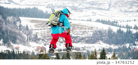 Young woman on the snowboard jumping 34763252