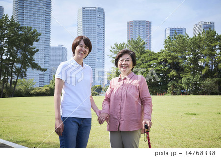 杖をついてお散歩する笑顔のシニアとヘルパーさん 34768338