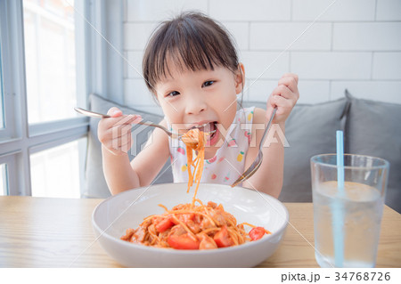 Little girl enjoy eating spaghetti on table  34768726