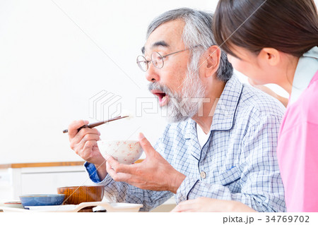 若い介護士とおじいちゃん　食事を楽しむ　会話　介助　栄養管理　老人ホーム　デイケアセンター 34769702
