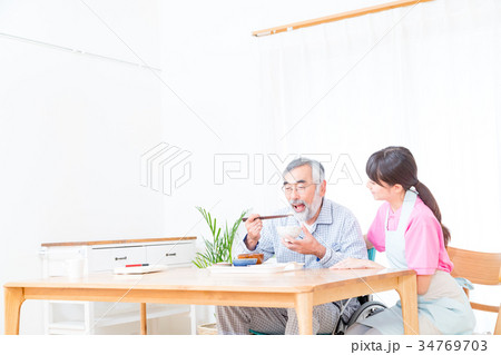 若い介護士とおじいちゃん　食事を楽しむ　会話　介助　栄養管理　老人ホーム　デイケアセンター 34769703