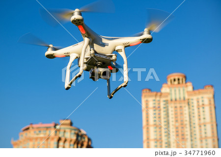 Drone quad copter with camera flying over the city Drone quad copter with camera flying over the city 34771960