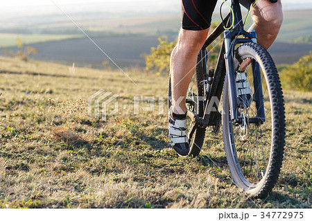 Closeup of cyclist man legs riding mountain bike Closeup of cyclist man legs riding mountain bike 34772975