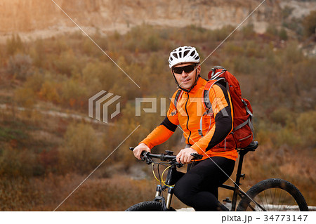 back view of a man with a bicycle and red backpack 34773147