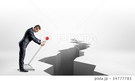 A businessman turns a large metal lever while 34777783