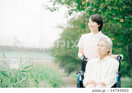 車椅子のシニアと若い介護士 新緑 車椅子のシニアと若い介護士 新緑 34794800